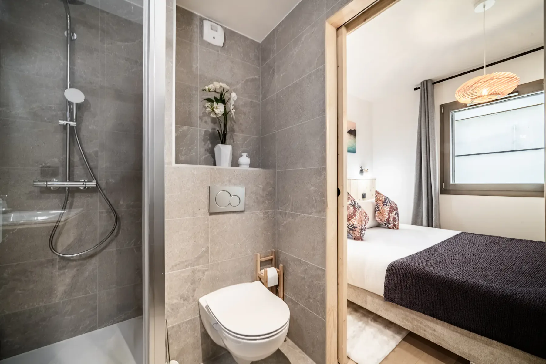 A bathroom with a shower and toilet beside a bedroom with a bed.