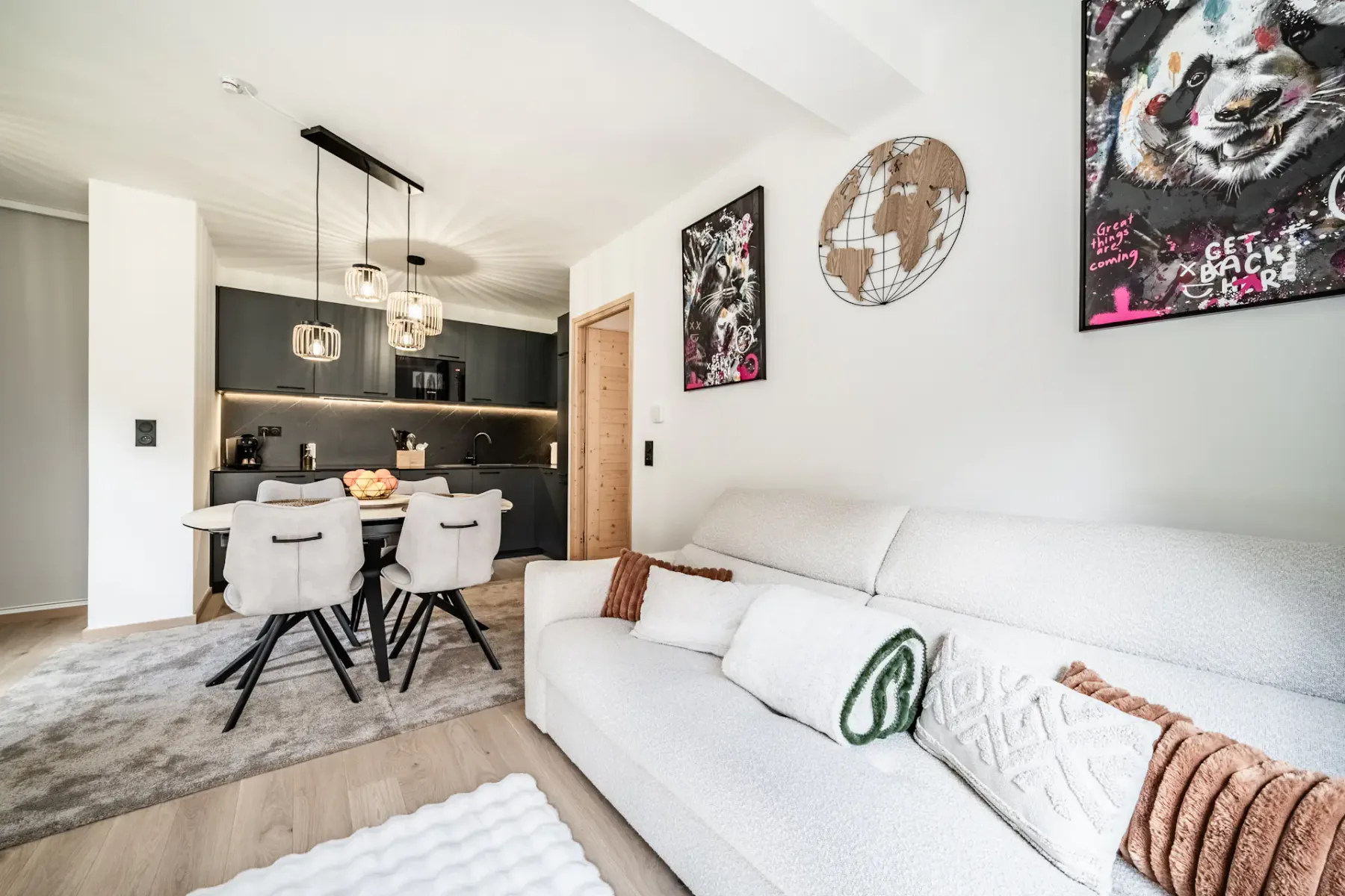 Bright living room with white seating, a dining area, and dark kitchen cabinetry.