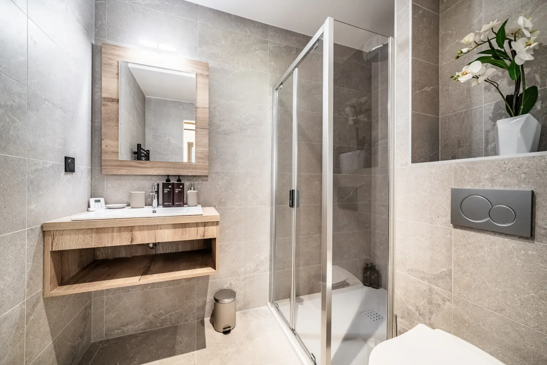 A tiled bathroom with a sink, mirror, and glass shower.