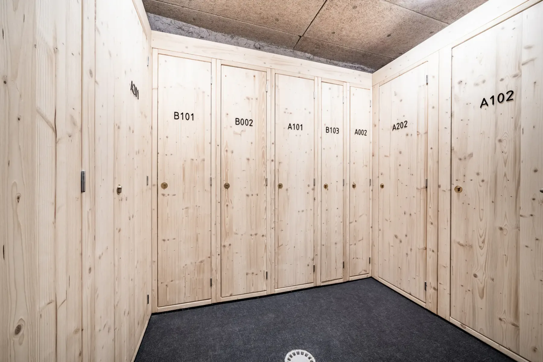 A storage room lined with pale wooden lockers and a dark floor.