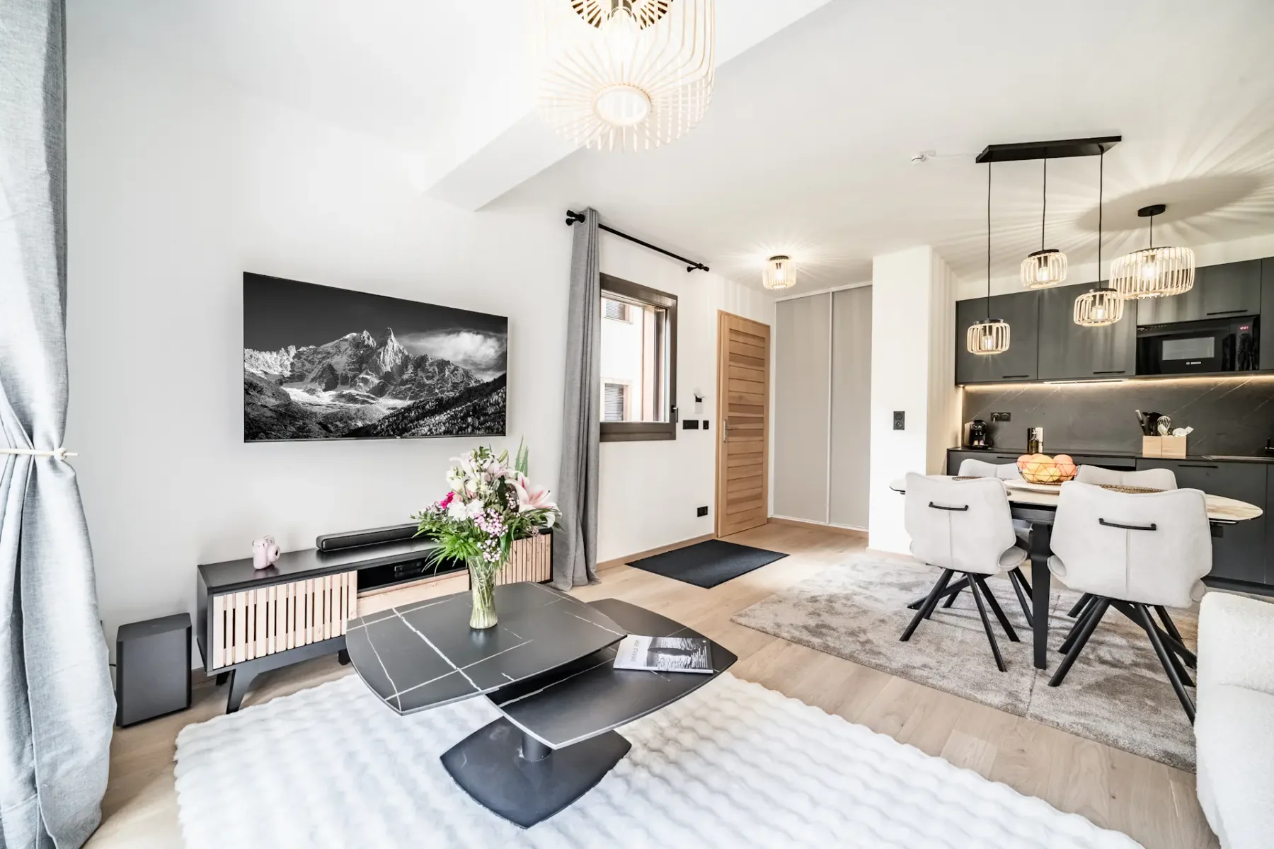 Bright open-plan living and dining area with contemporary seating and a kitchen beyond.