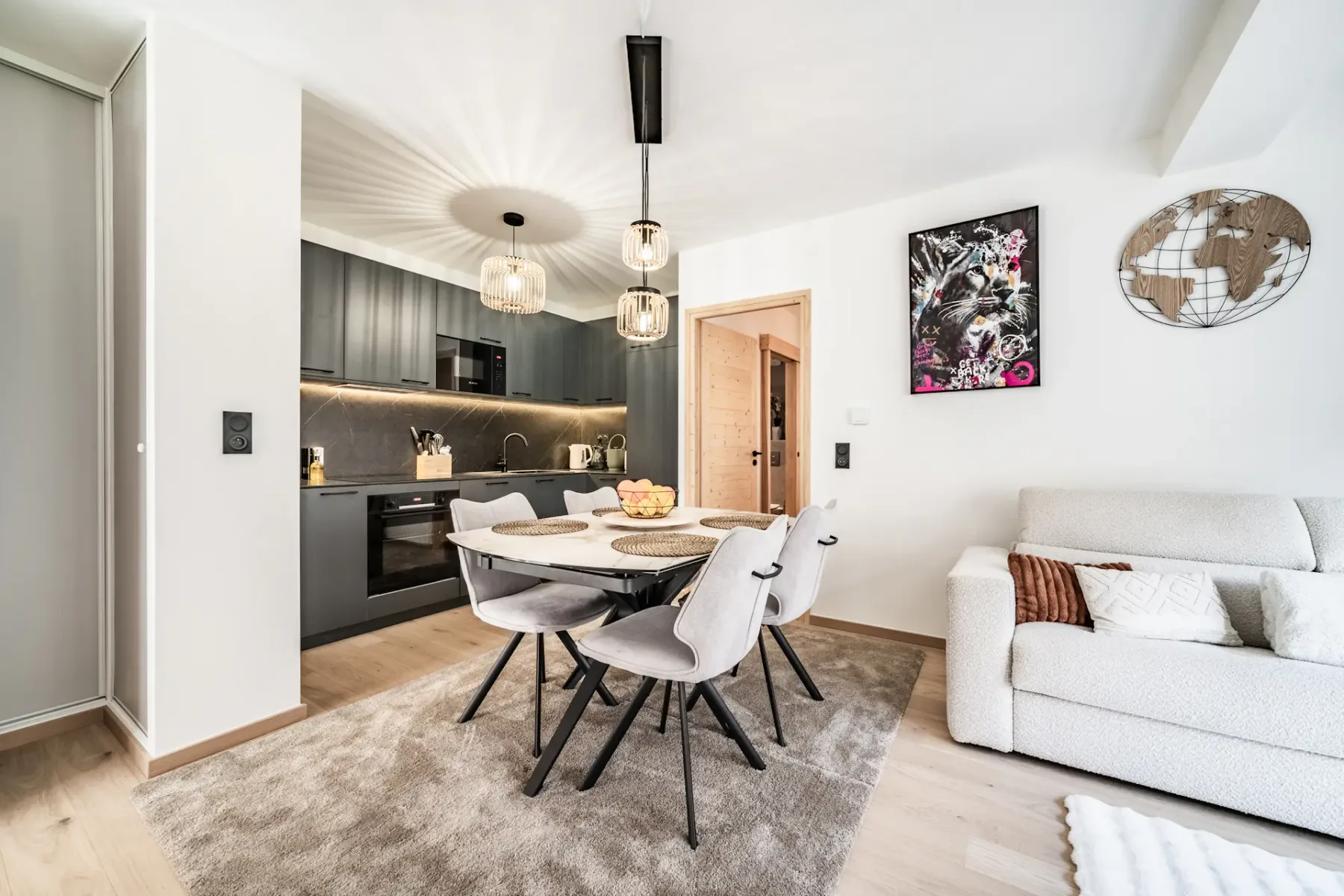 A modern open-plan living and dining area with a table and pendant lights.