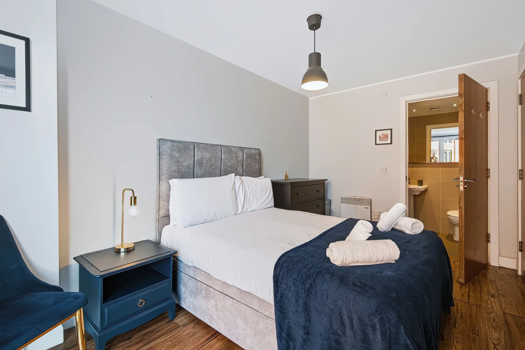 A bedroom with a bed, bedside table, and an open doorway to a bathroom.