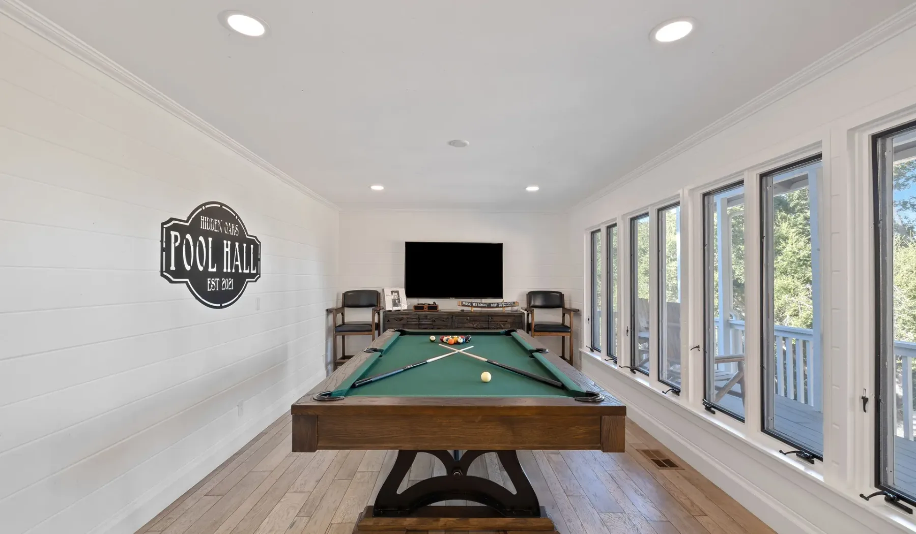 Una luminosa sala de juegos con una mesa de billar y ventanas grandes.