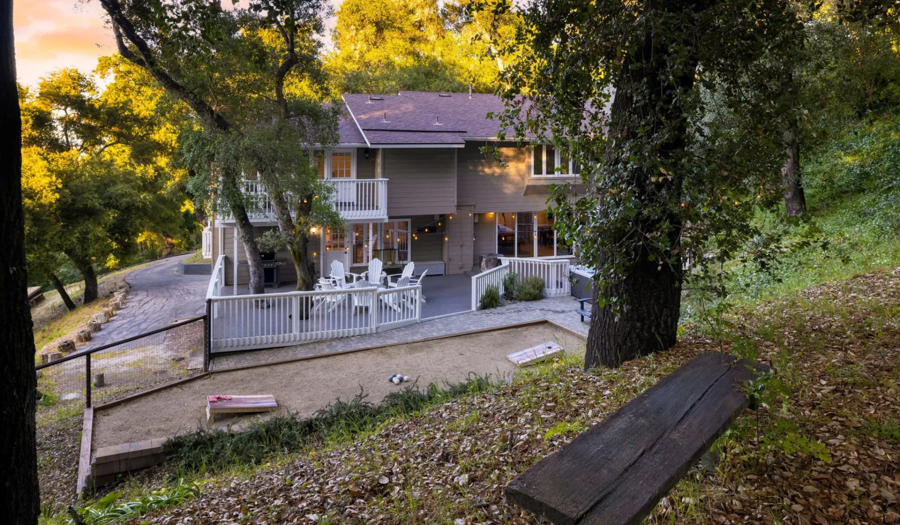 Una casa elevada con un patio cercado está rodeada de árboles maduros.