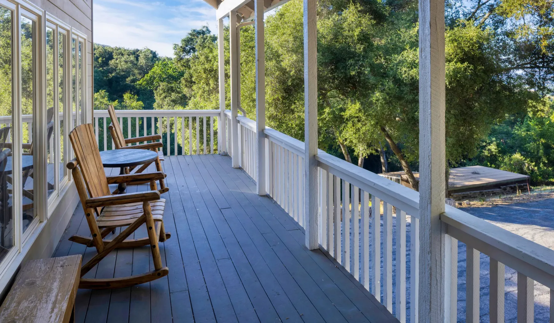 Una terraza exterior cubierta con asientos de madera da a árboles frondosos.