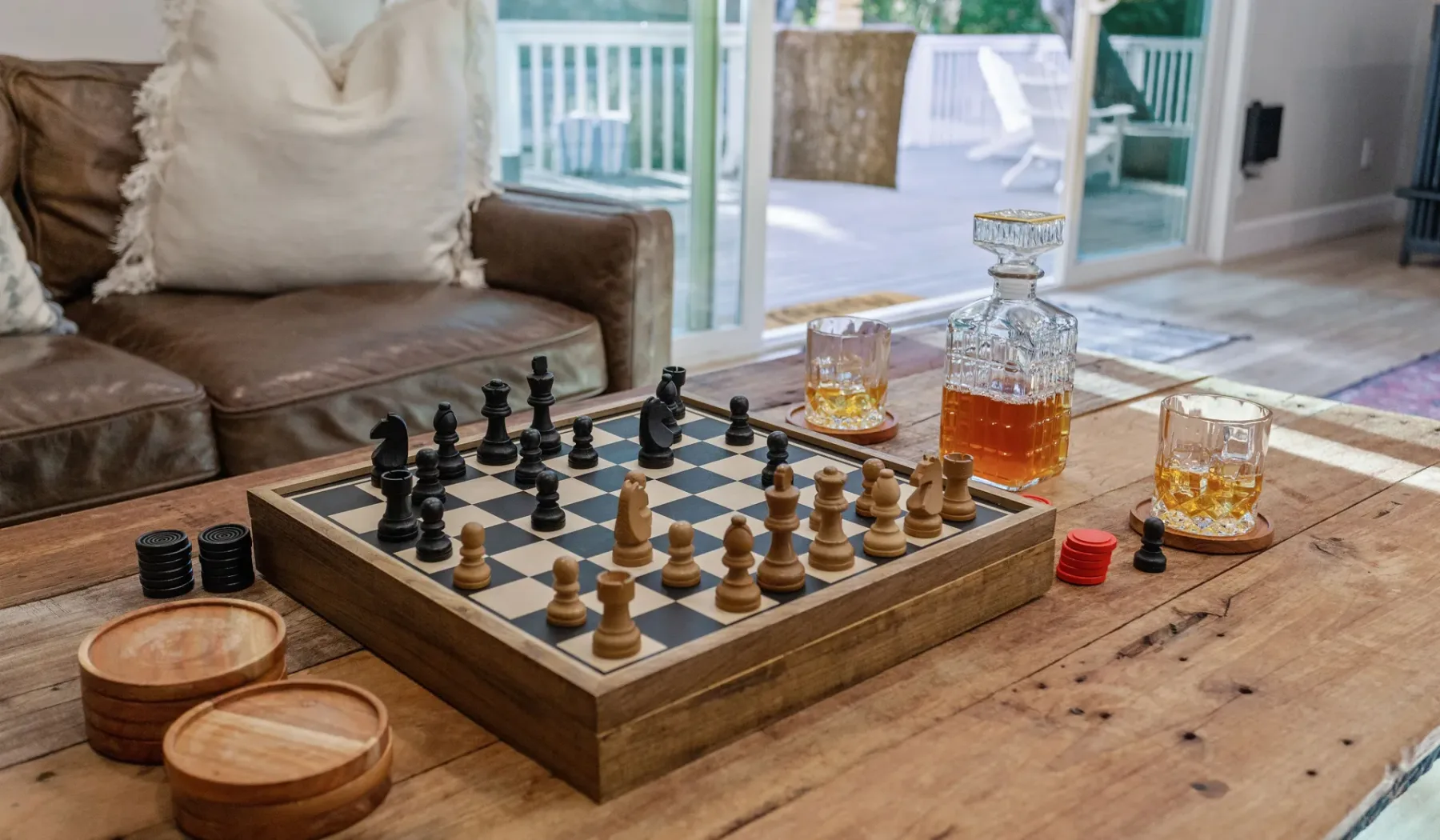 Una sala de estar con un tablero de ajedrez y bebidas sobre una mesa de centro de madera.