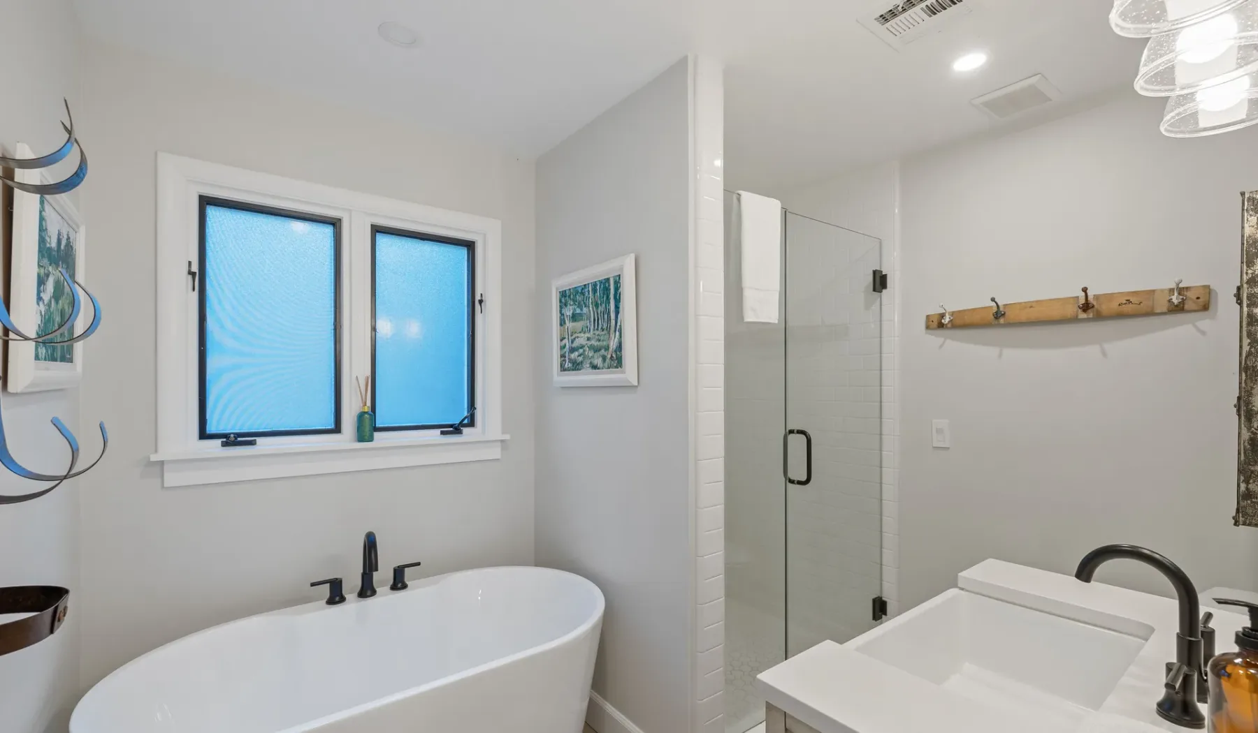 Un baño luminoso con bañera exenta, ducha de vidrio y lavabo.