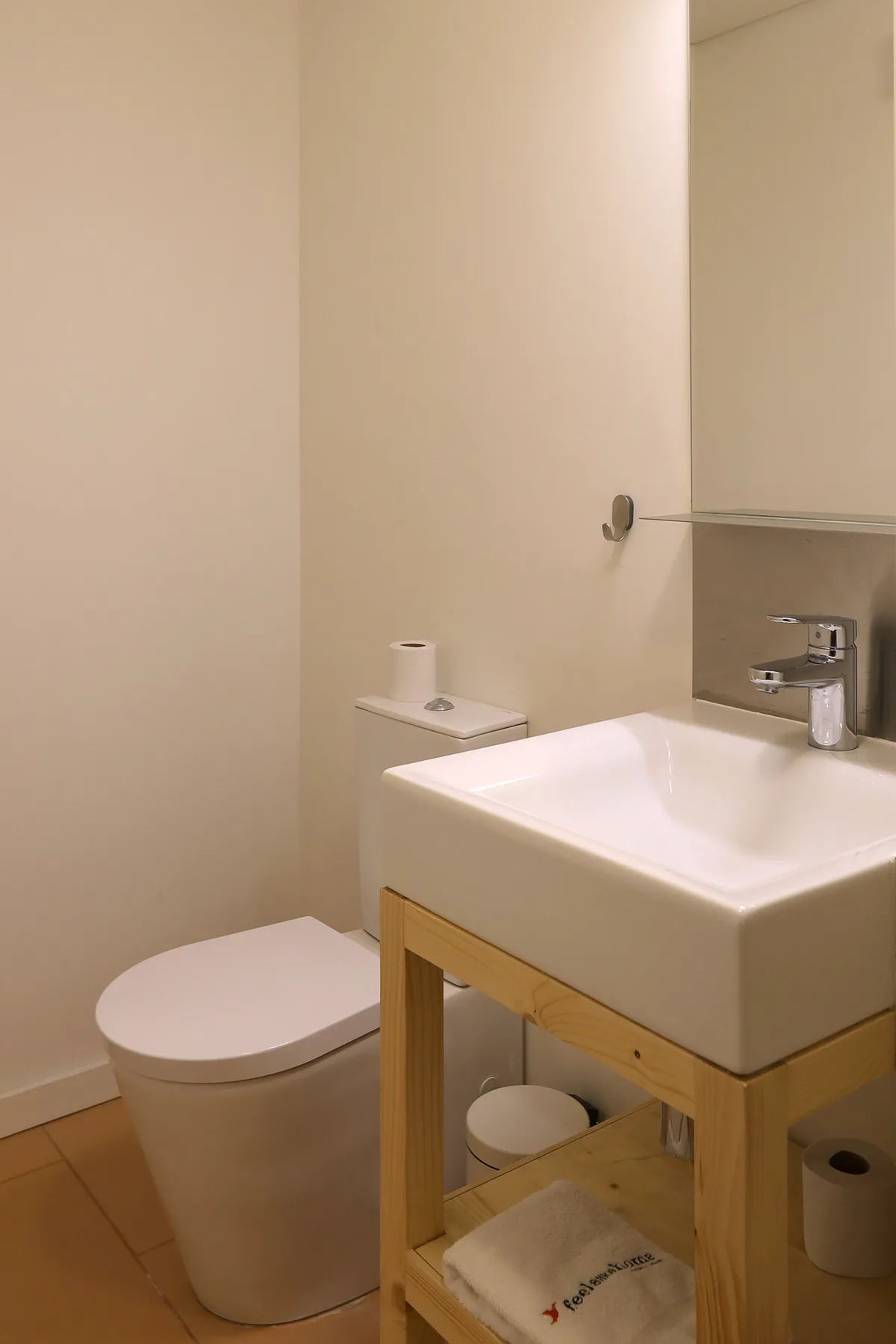 A bathroom with a toilet and a sink on a wooden stand.