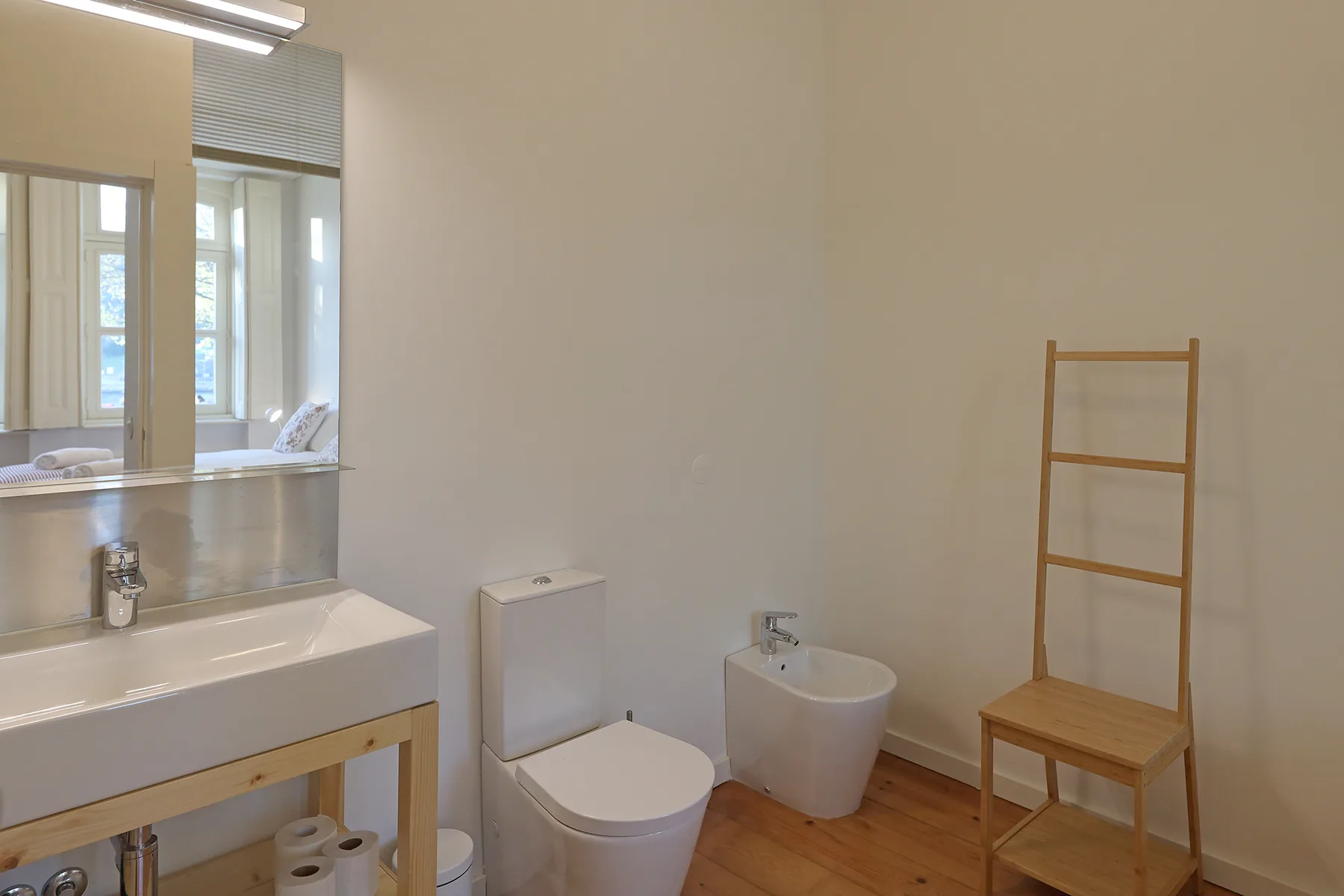 A bright bathroom with a sink, toilet, and bidet.
