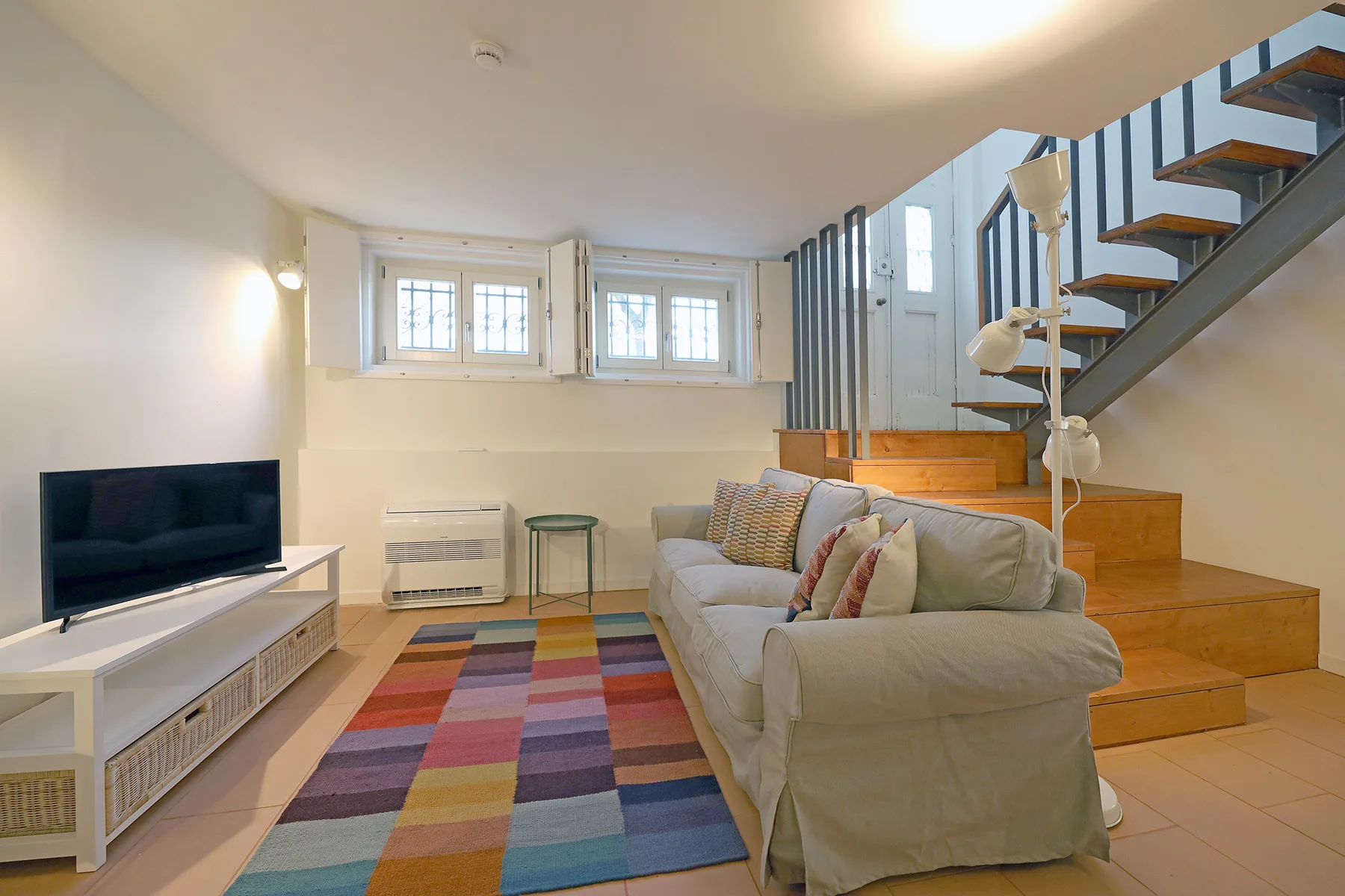 A living room with a sofa, television, and staircase.