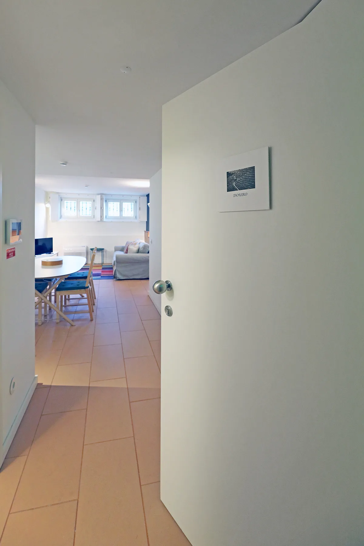 An open doorway looks into a living and dining area with a table and seating.