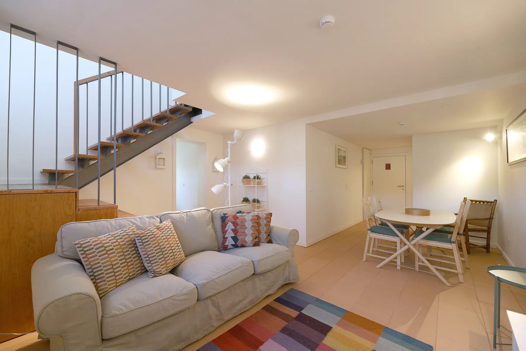 Living room with seating beside a dining table and staircase.