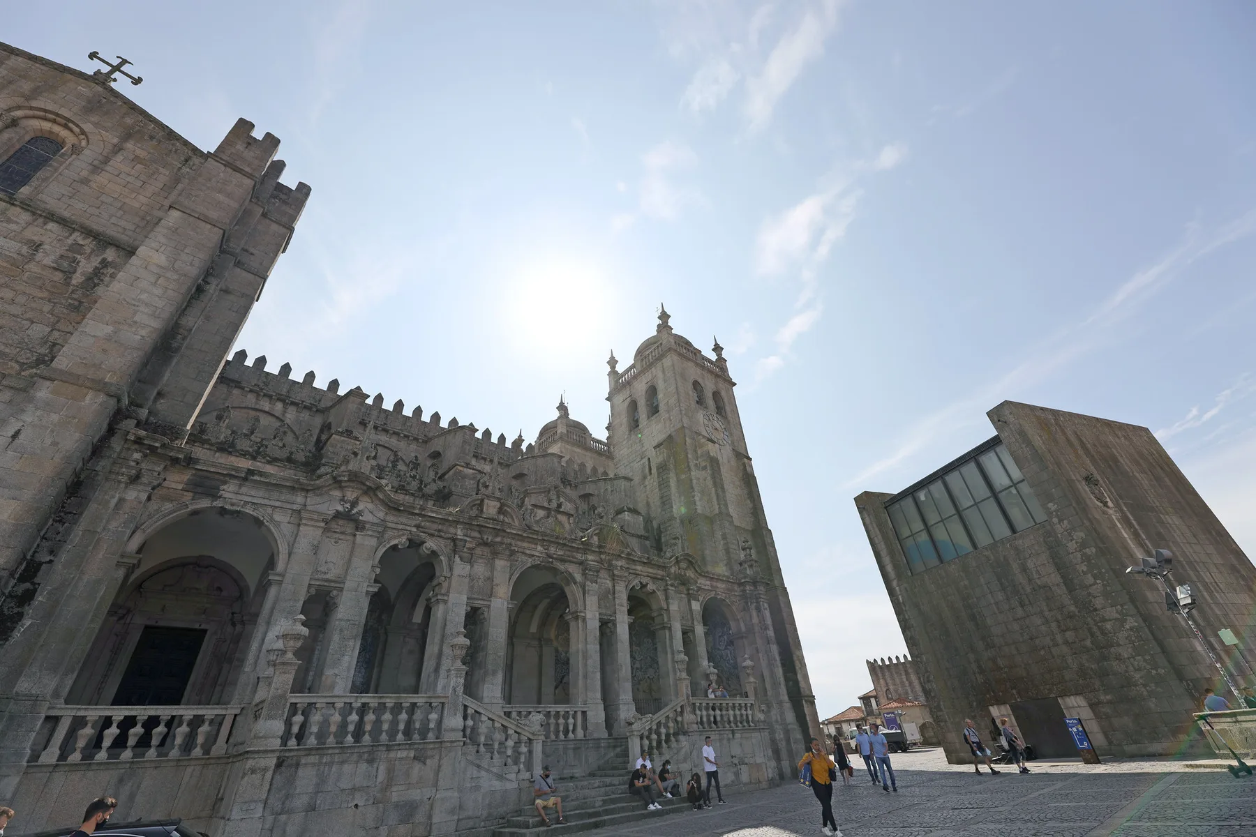 A historic stone church facade and tower stand beside a modern angular building.