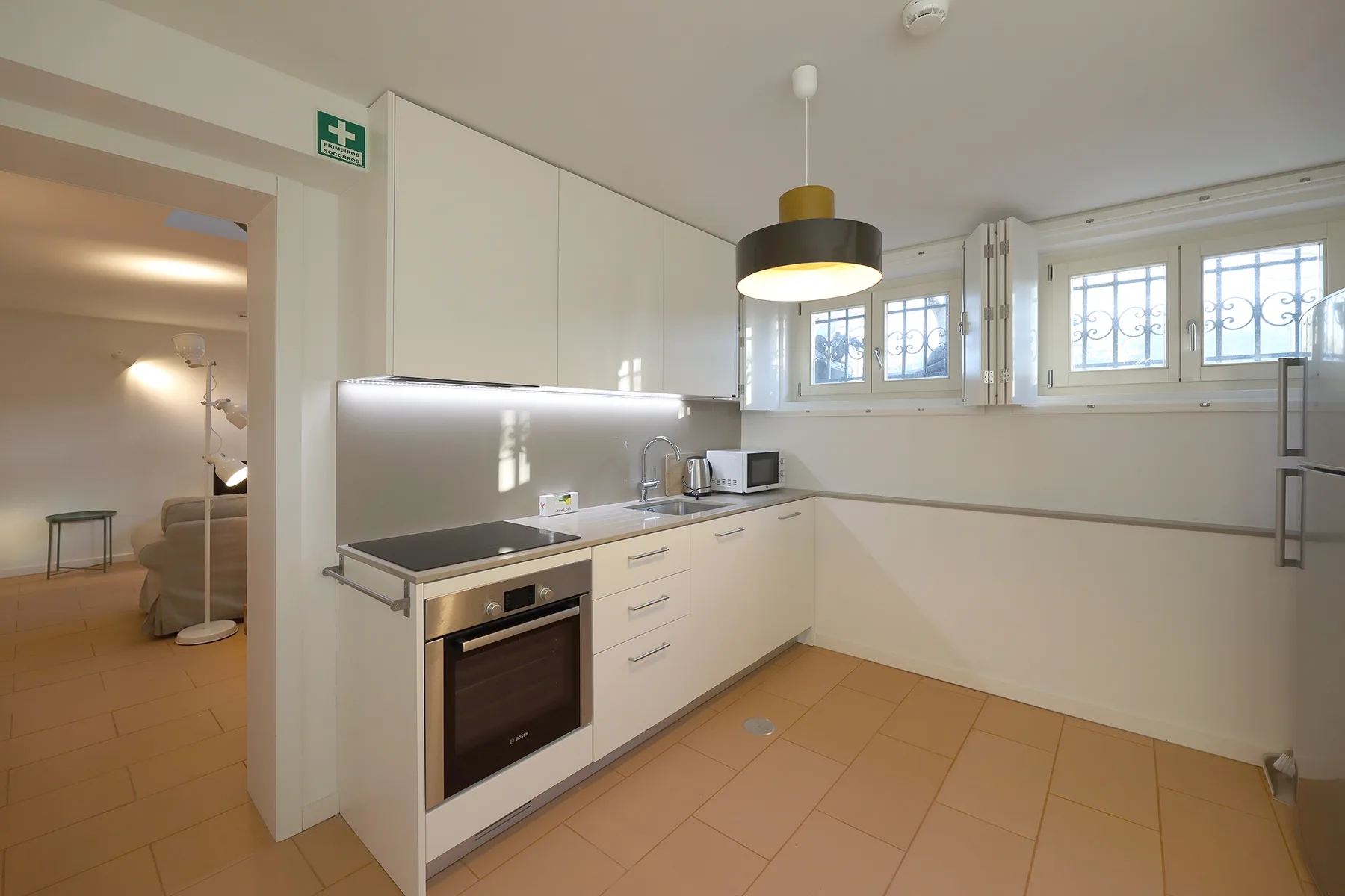 A bright kitchen with a cooktop, oven, and windows along the counter.
