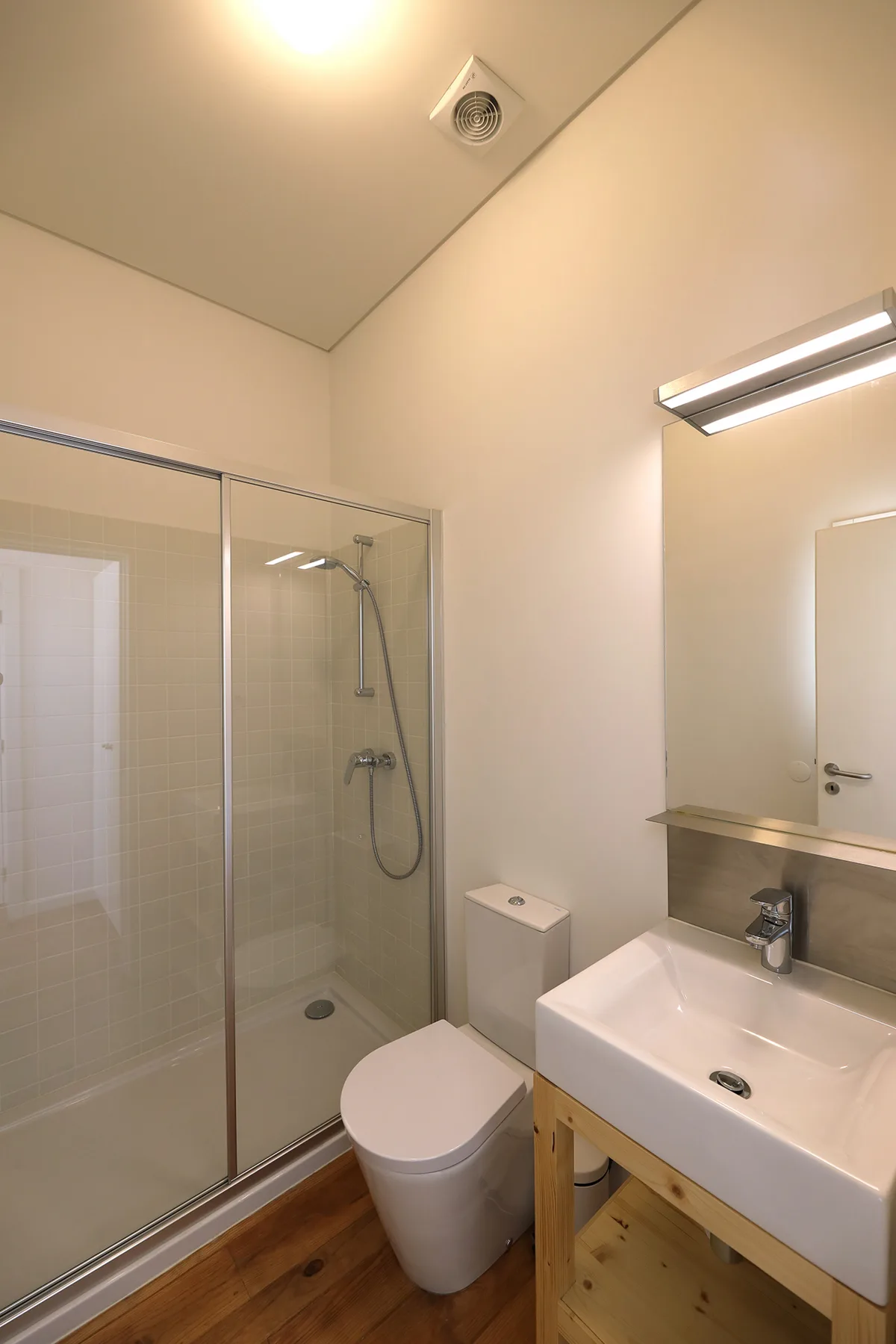 A bathroom with a glass shower, toilet, and sink.