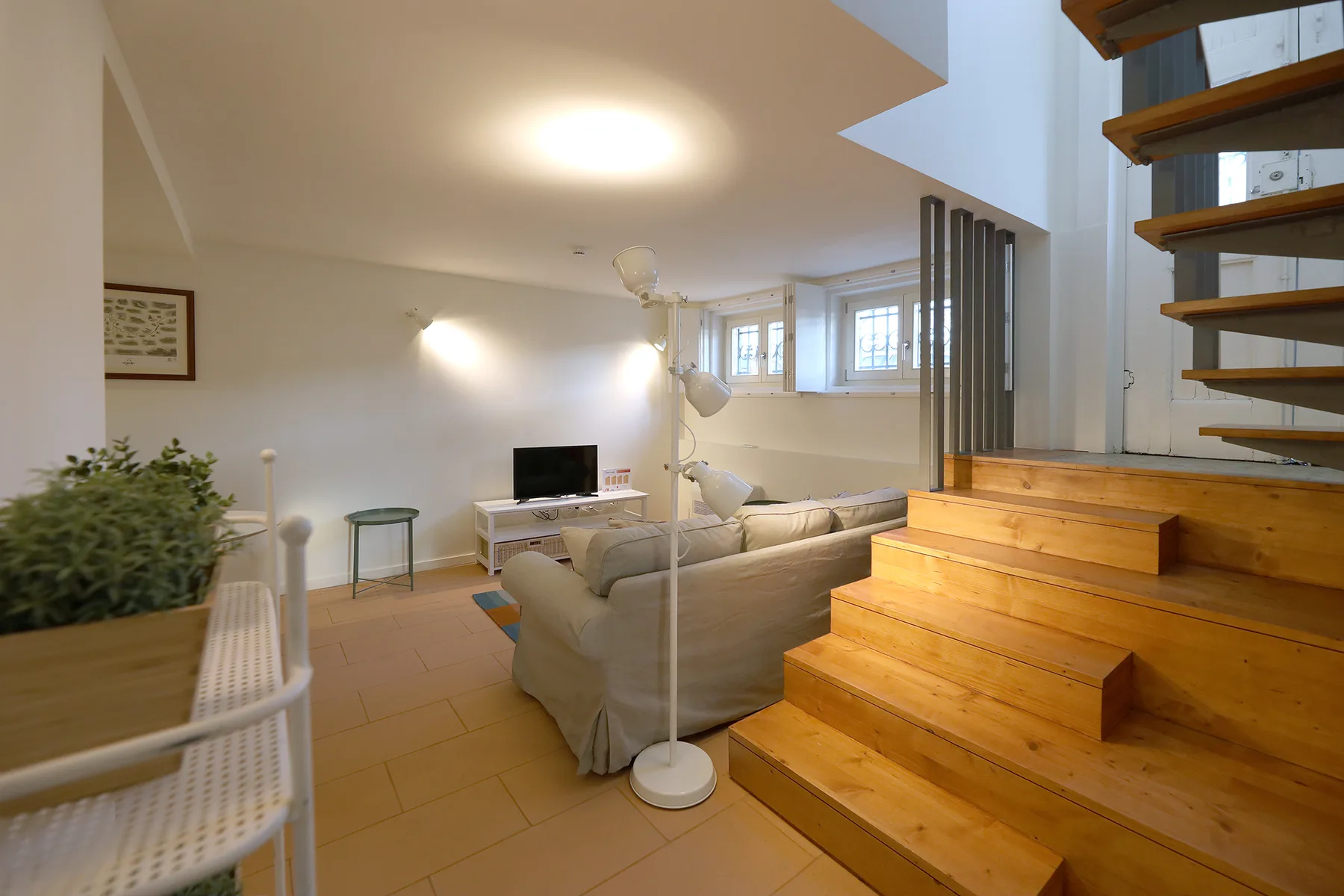 A living room with seating, a television, and wooden stairs.