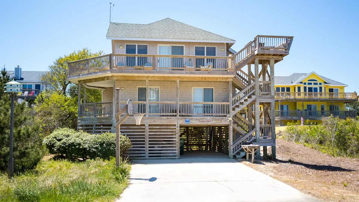 Una casa elevada con terraza de madera y escaleras exteriores.