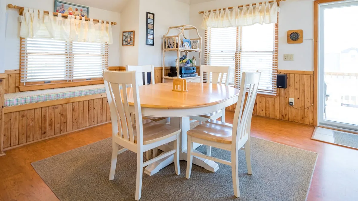 Un comedor con una mesa de madera y sillas sobre una alfombra.