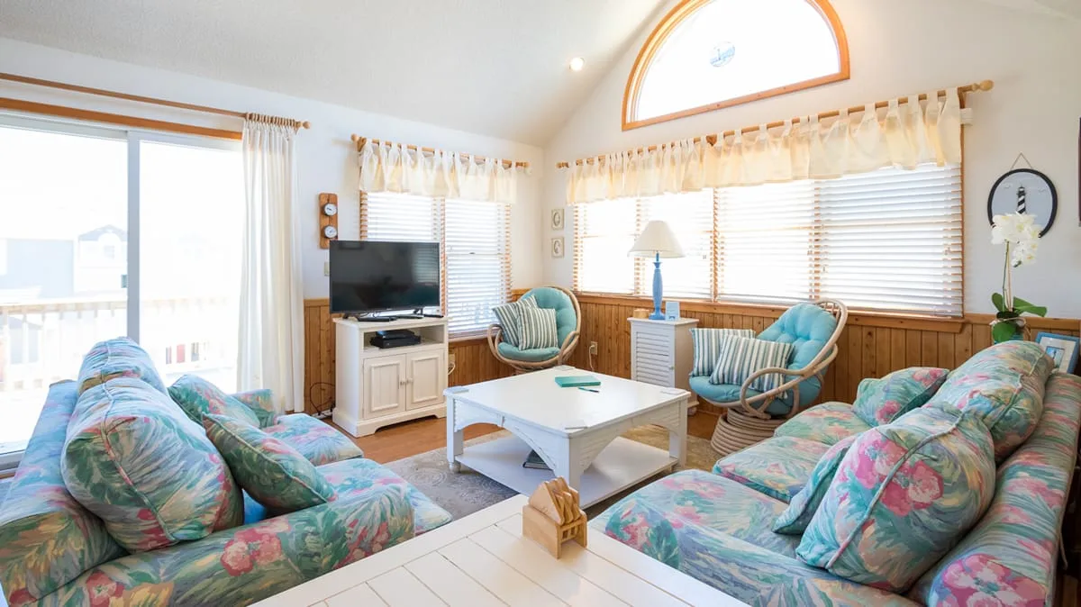 A bright living room with floral seating and a coffee table.