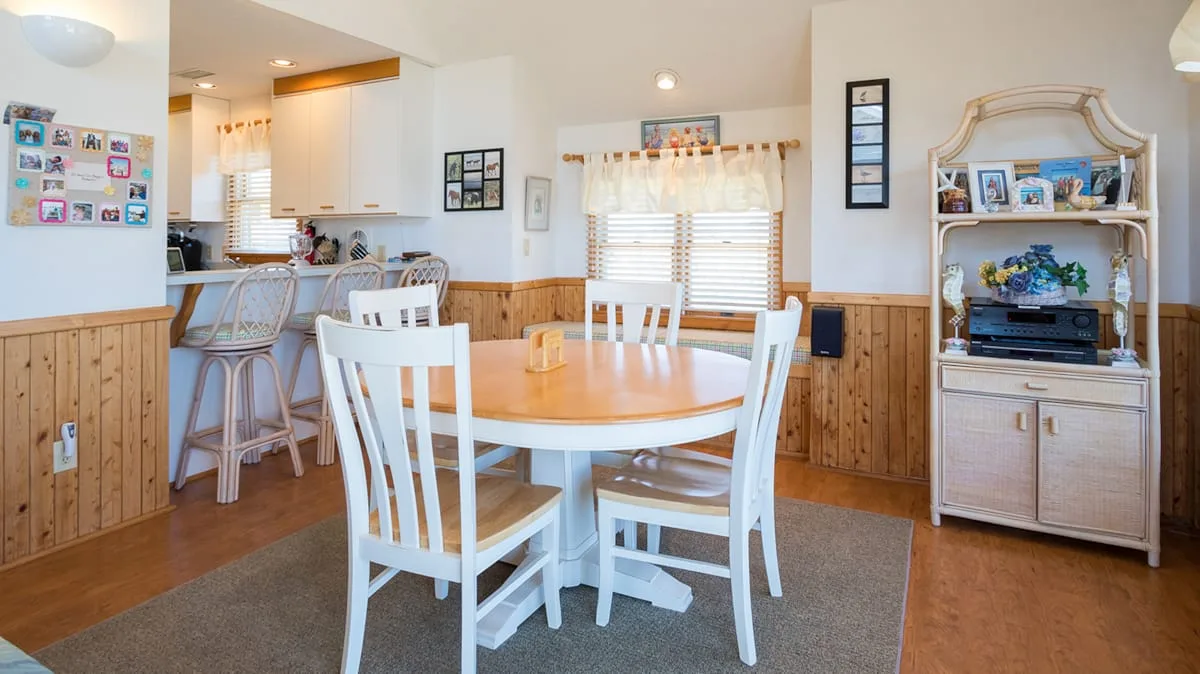 Comedor con una mesa redonda y sillas blancas junto a una cocina abierta.