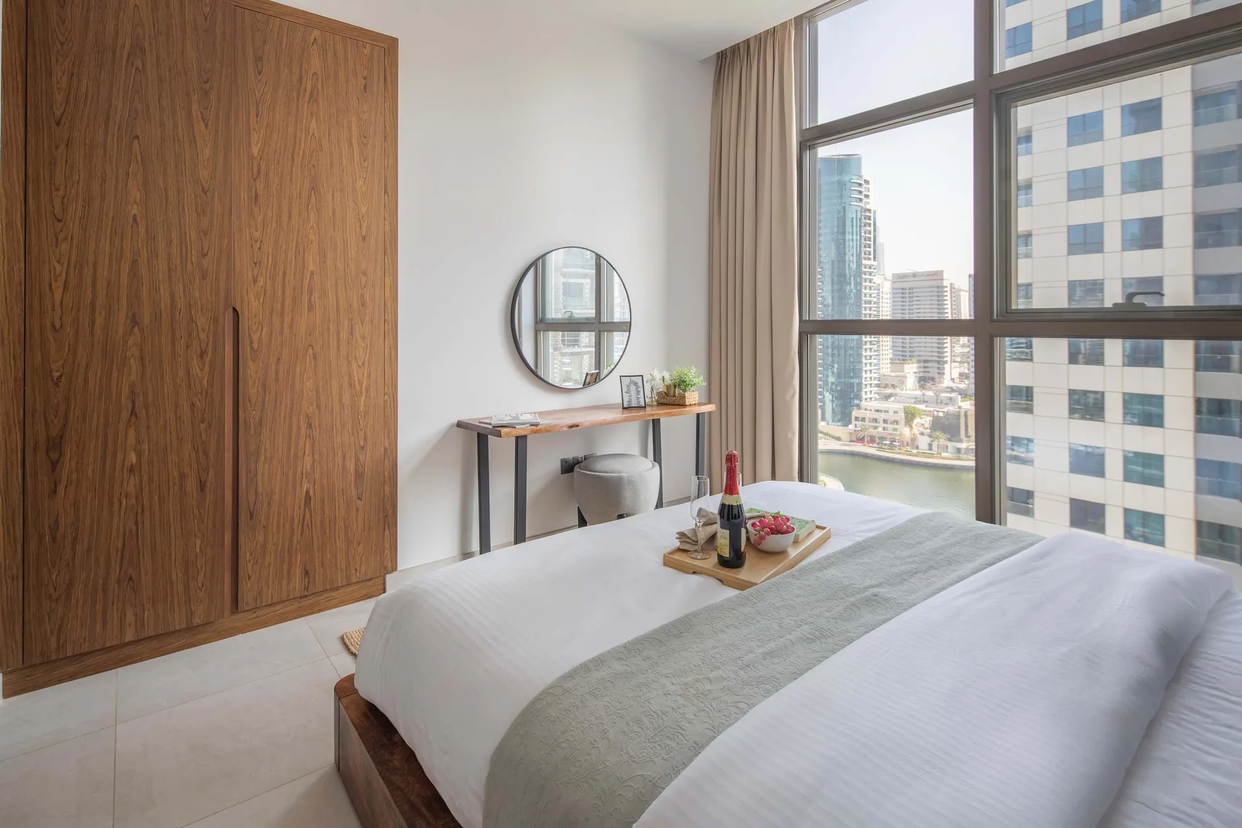 Un dormitorio con una cama bien tendida junto a una ventana grande.