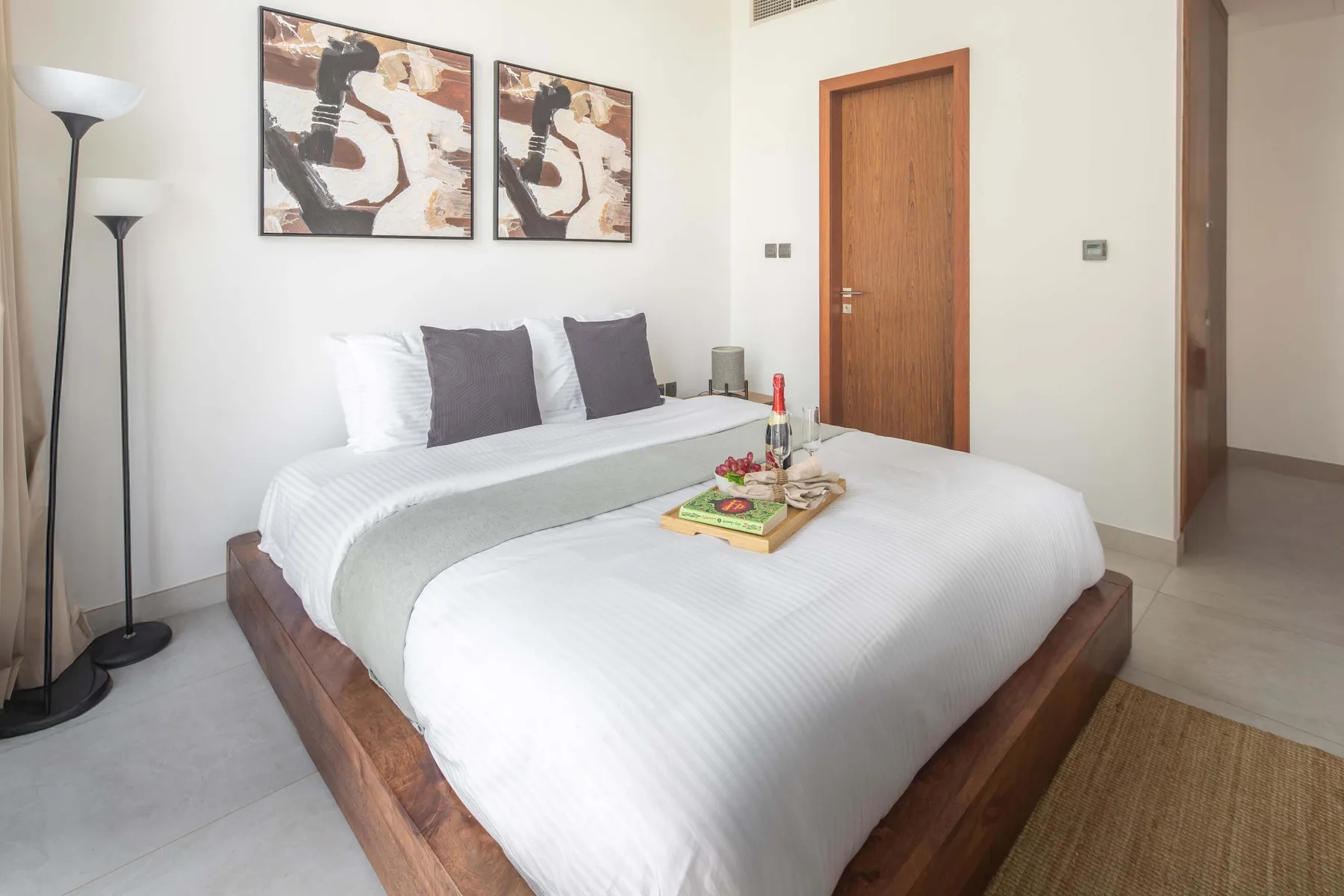 Un dormitorio con una cama bien tendida y cuadros abstractos enmarcados en la pared.