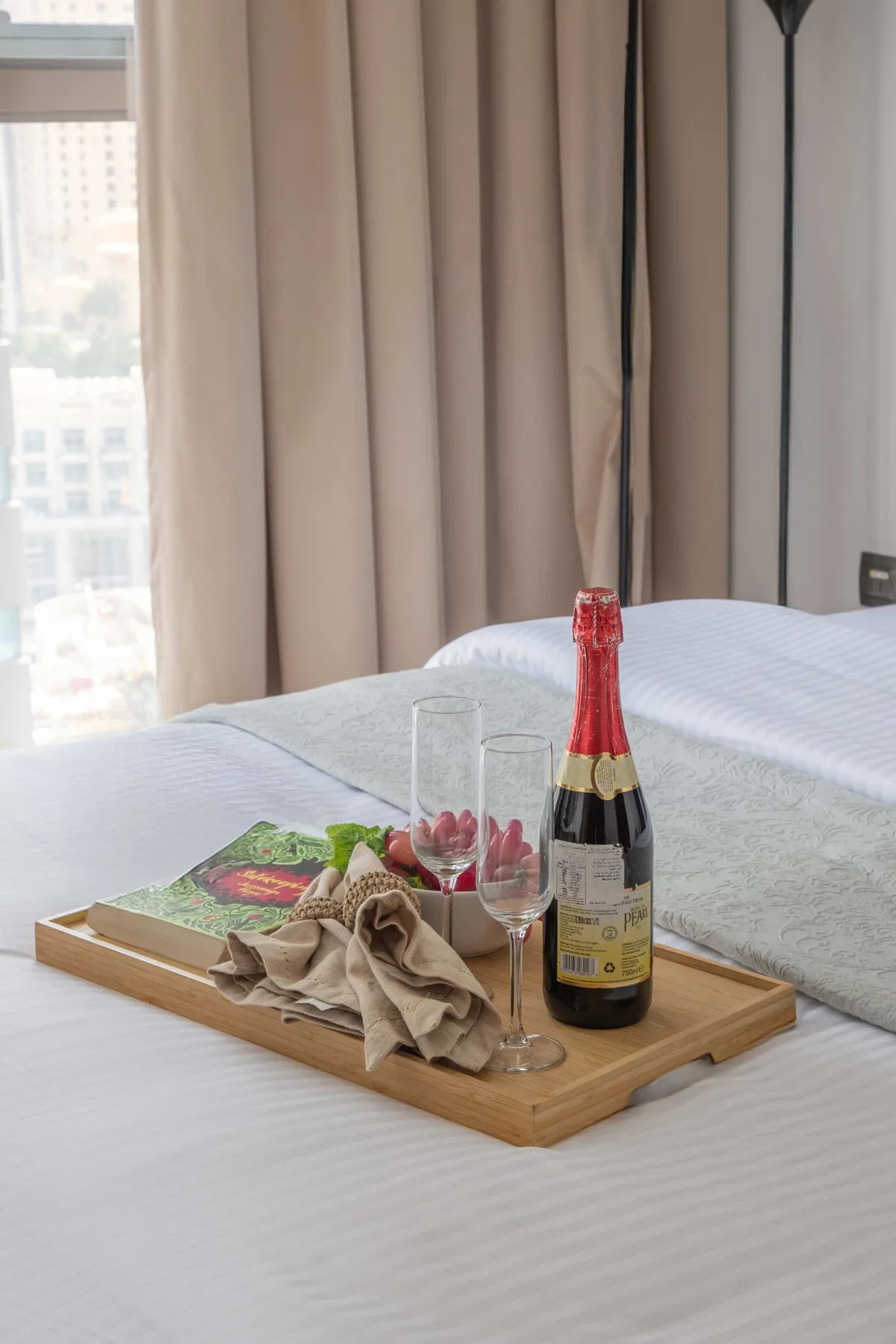Un dormitorio con una bandeja de madera que sostiene una botella y dos copas sobre la cama.