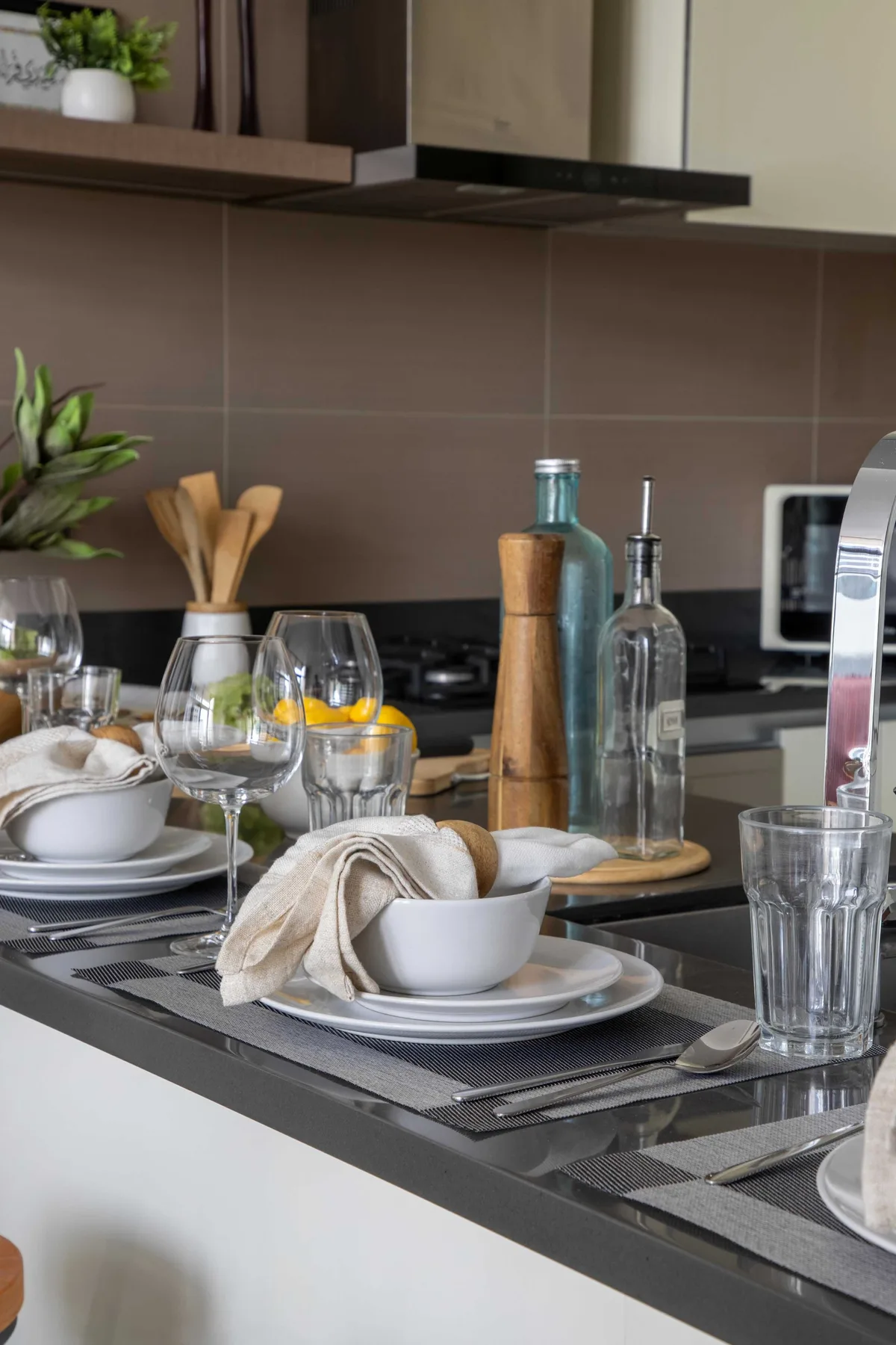 Una encimera de cocina está preparada con platos, vasos y utensilios.