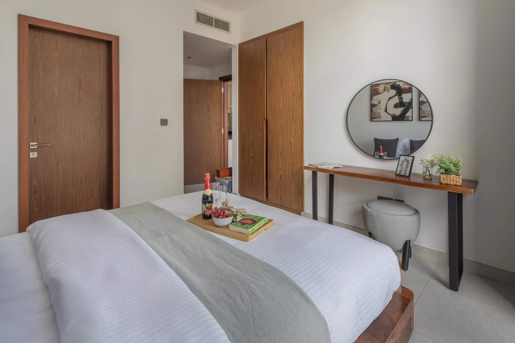 Dormitorio con una cama tendida, puertas de madera y una mesa consola.