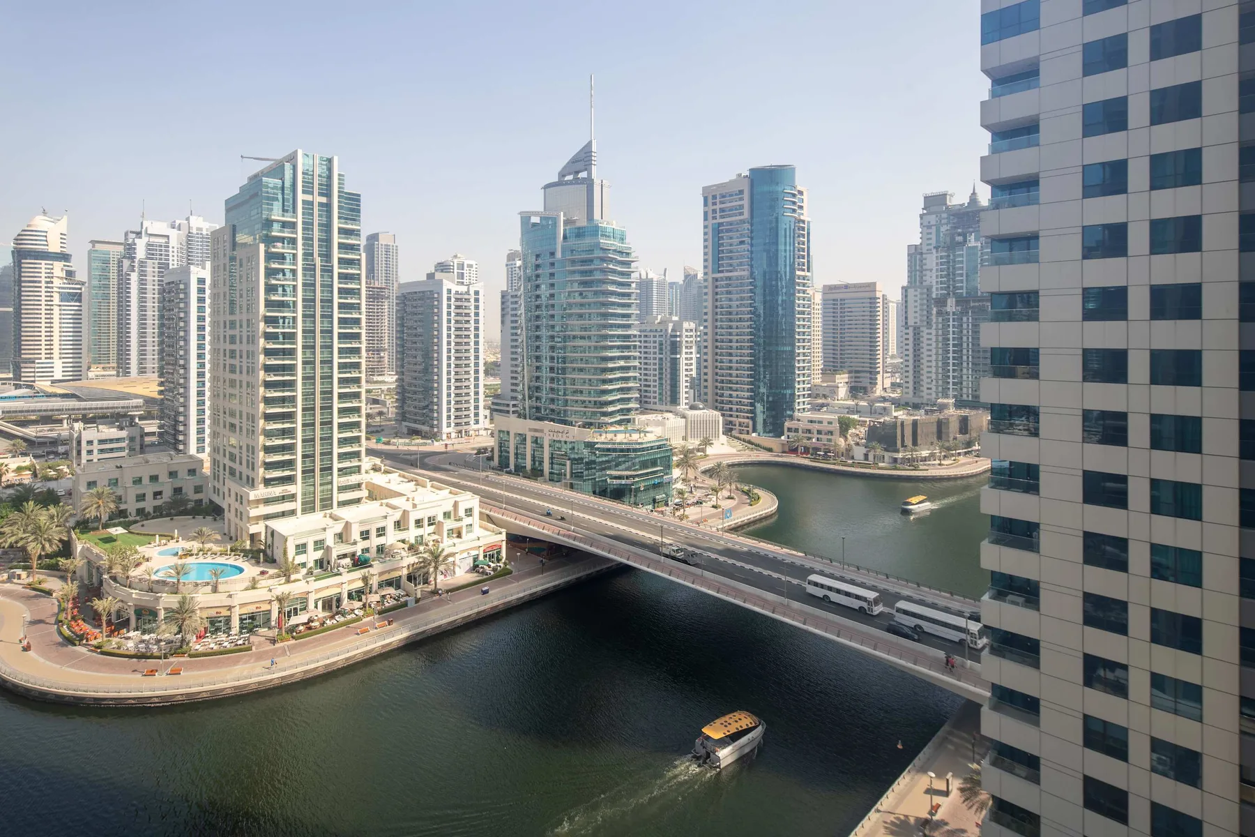 Un paisaje urbano frente al agua, con edificios altos, un puente y barcos.