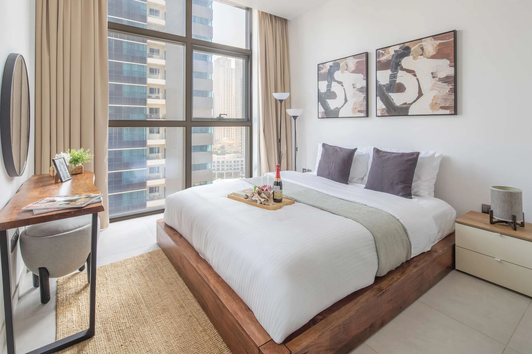 Un dormitorio luminoso con una cama bien tendida junto a grandes ventanas.