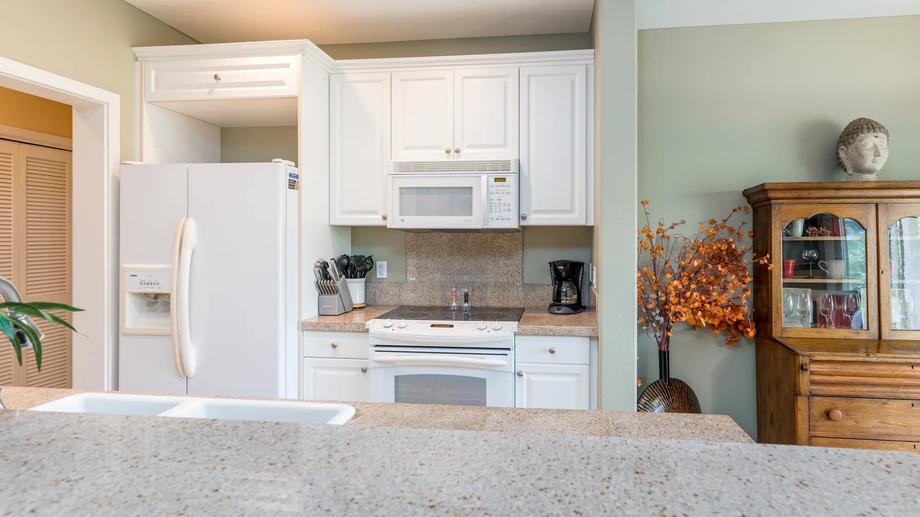 Una cocina luminosa con gabinetes blancos, un refrigerador y una encimera en primer plano.