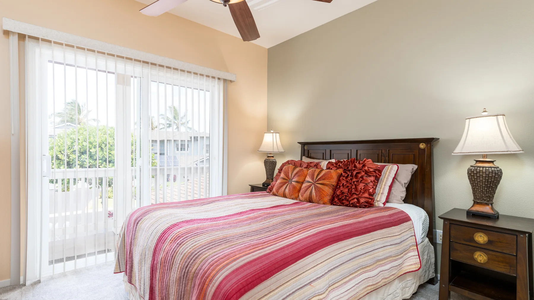 Un dormitorio con una cama bien tendida junto a una puerta corrediza de vidrio luminosa.