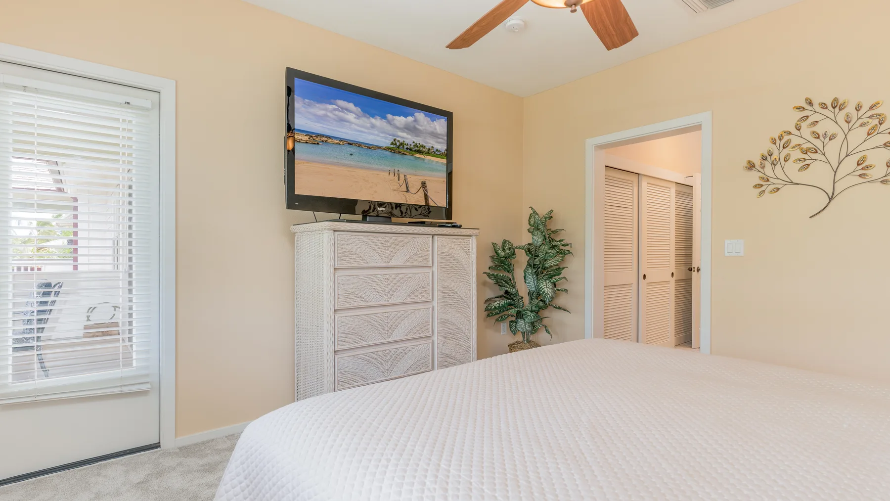 Un dormitorio con cama, cómoda y televisor montado en la pared.