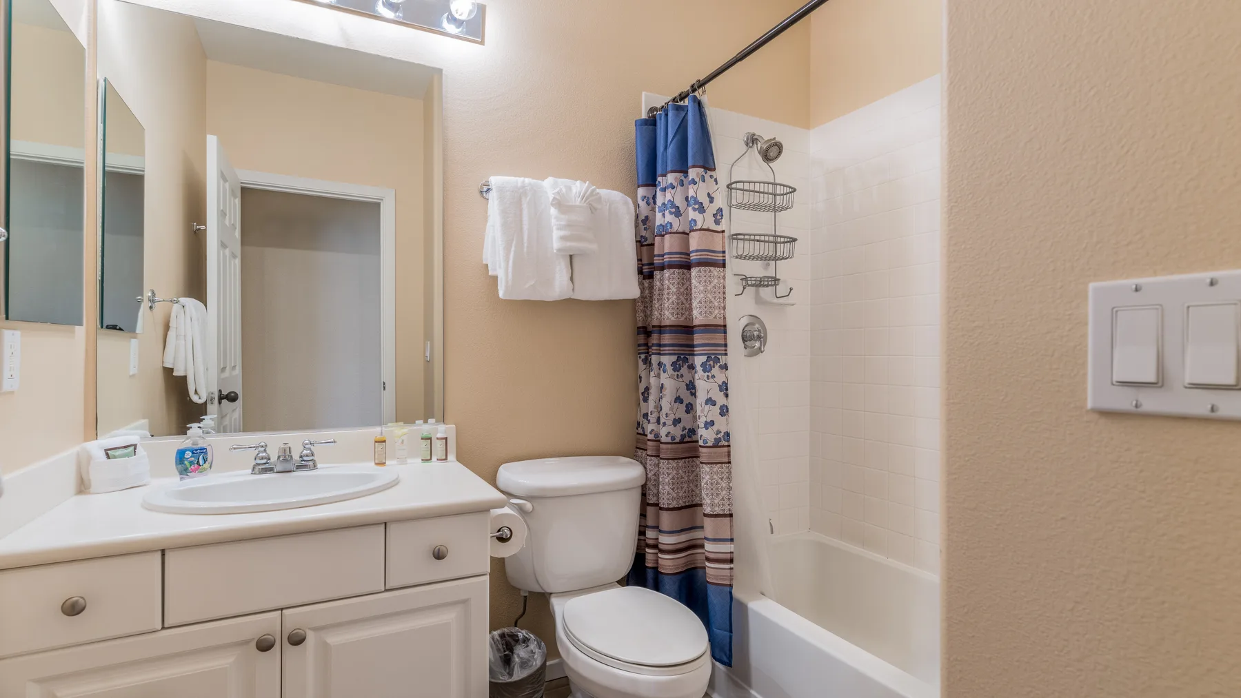 Un baño con lavabo, inodoro y bañera detrás de una cortina de ducha.