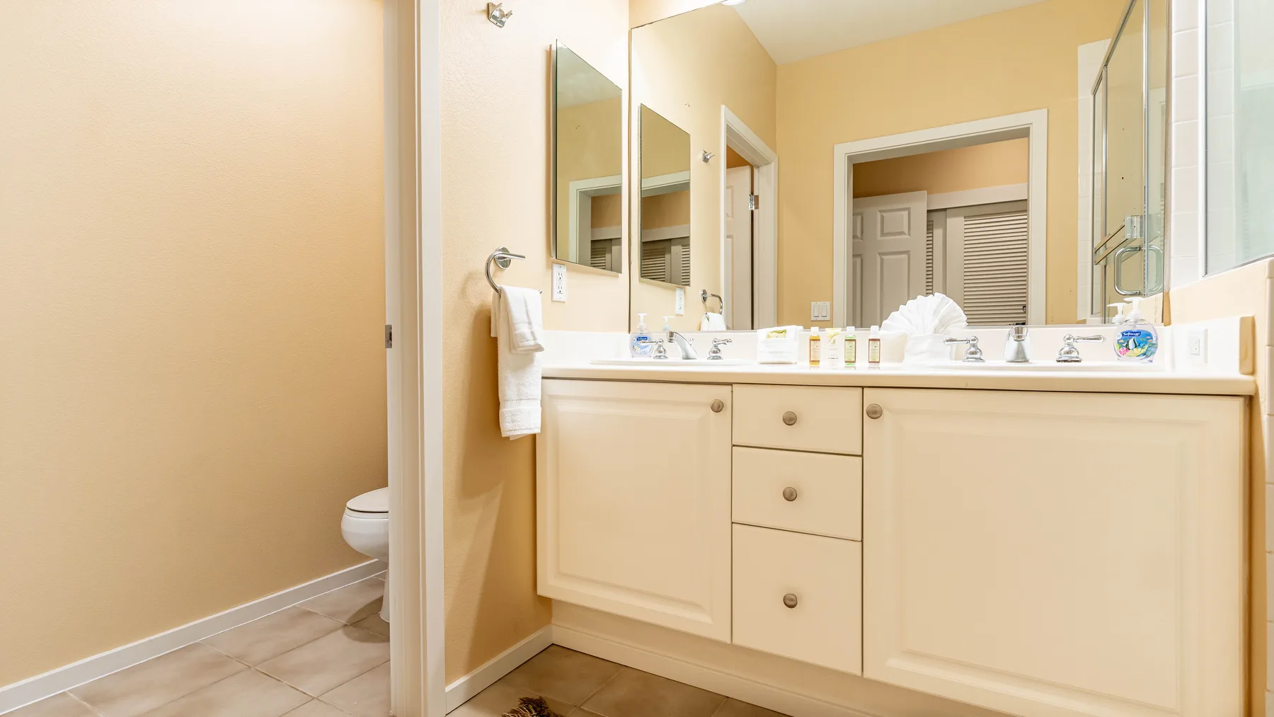 Un tocador de baño con lavabos y espejos está junto a una puerta abierta.