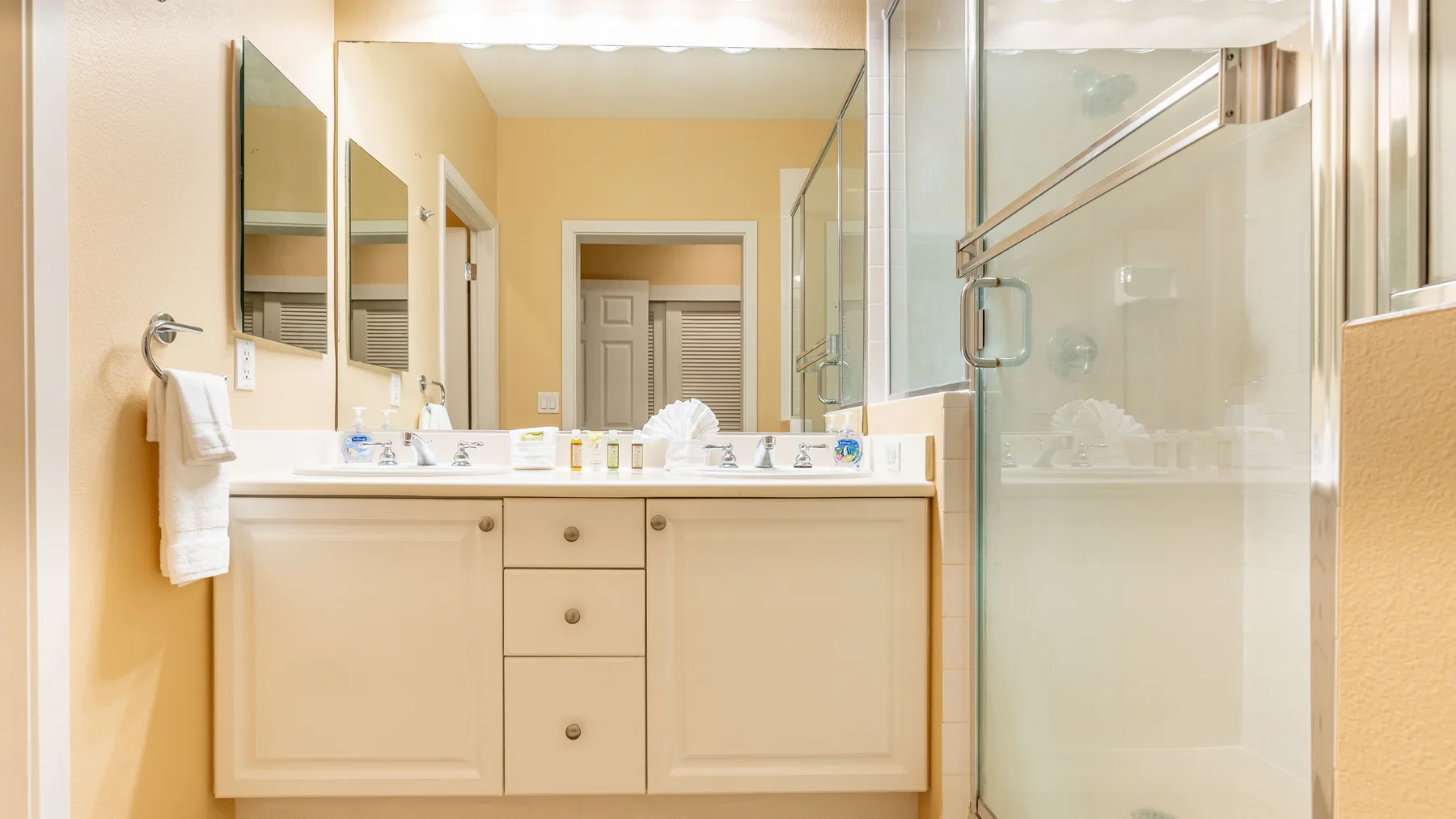 Un baño luminoso con un tocador largo y una ducha con mampara de vidrio.
