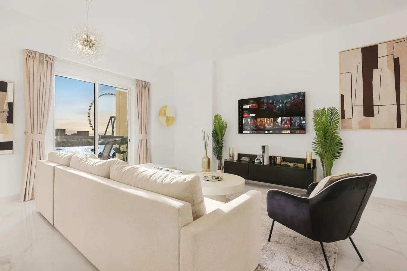 Una sala luminosa con asientos frente a un televisor y grandes ventanas.