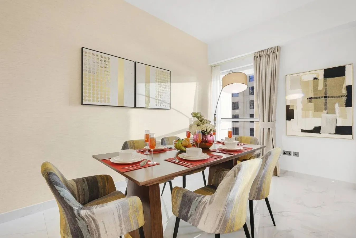 Un comedor con la mesa puesta, asientos tapizados y arte abstracto enmarcado.