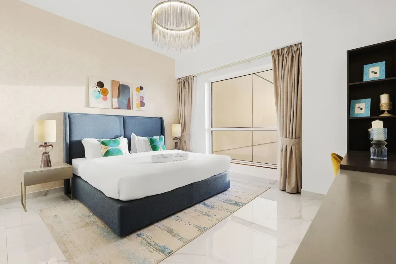 Un dormitorio con cama, mesa de noche y una gran ventana con cortinas.