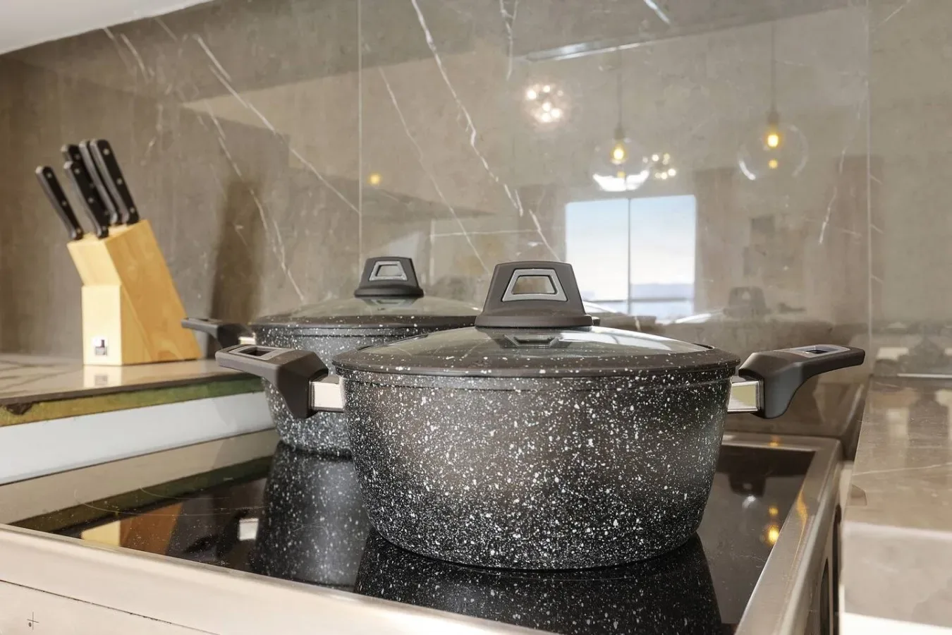 Una estufa de cocina con una olla moteada grande y un bloque de cuchillos cerca.