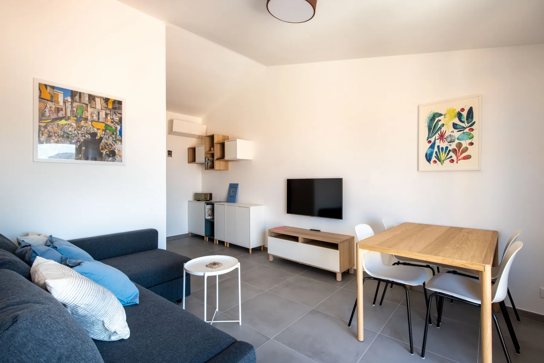 Una zona de estar y comedor con televisor, asientos y una mesa.