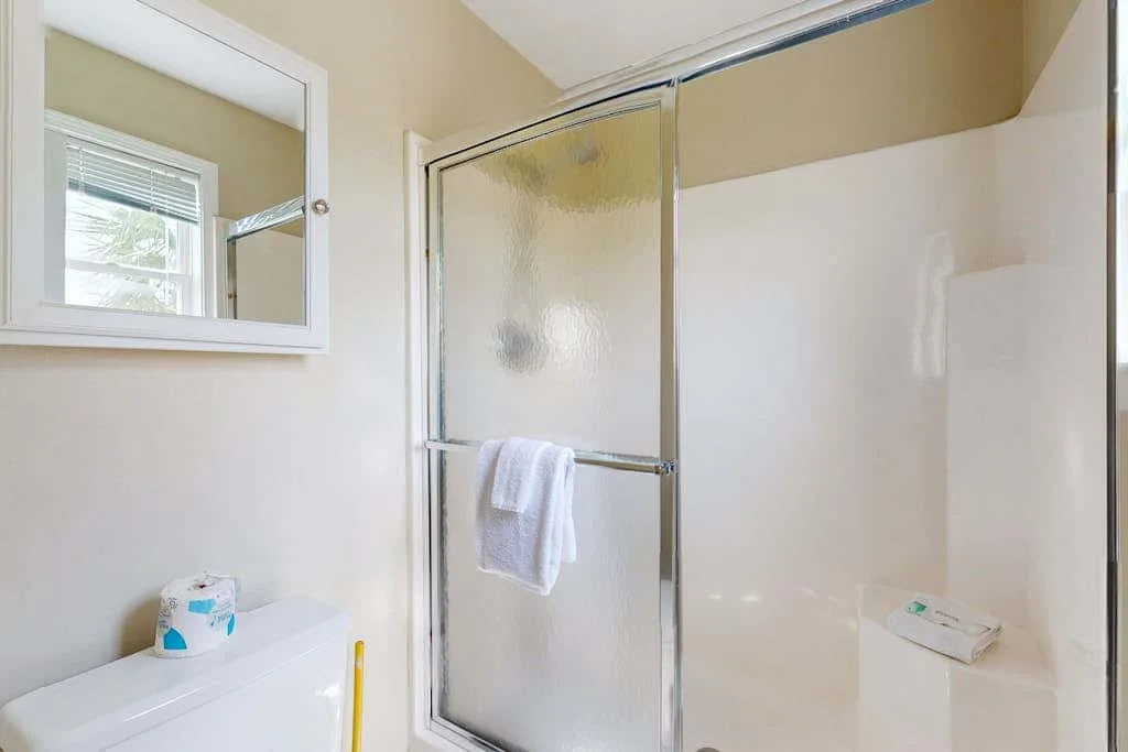 A bathroom with a glass shower and a small window.