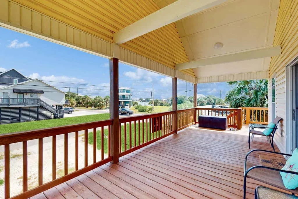 A covered outdoor deck with wooden railings and seating overlooks the surrounding homes.