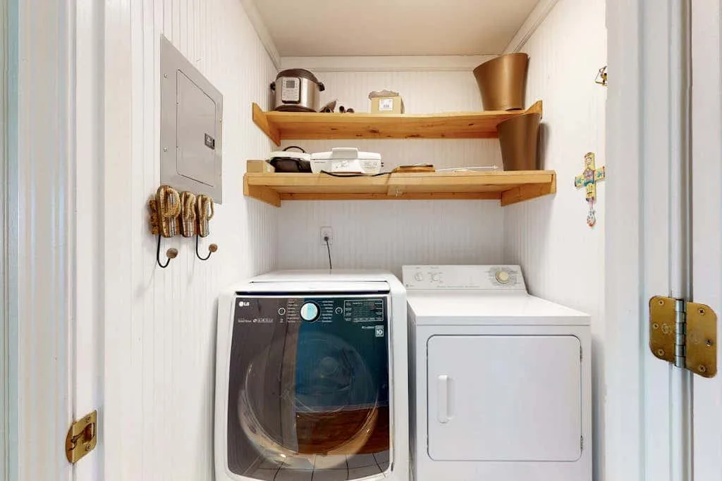 A laundry area with a front-loading washer and a dryer beneath wall shelves.