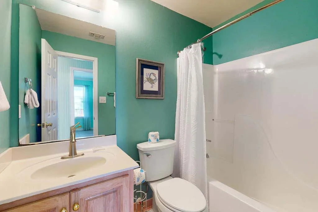 A bathroom with a sink, toilet, and a shower behind a white curtain.