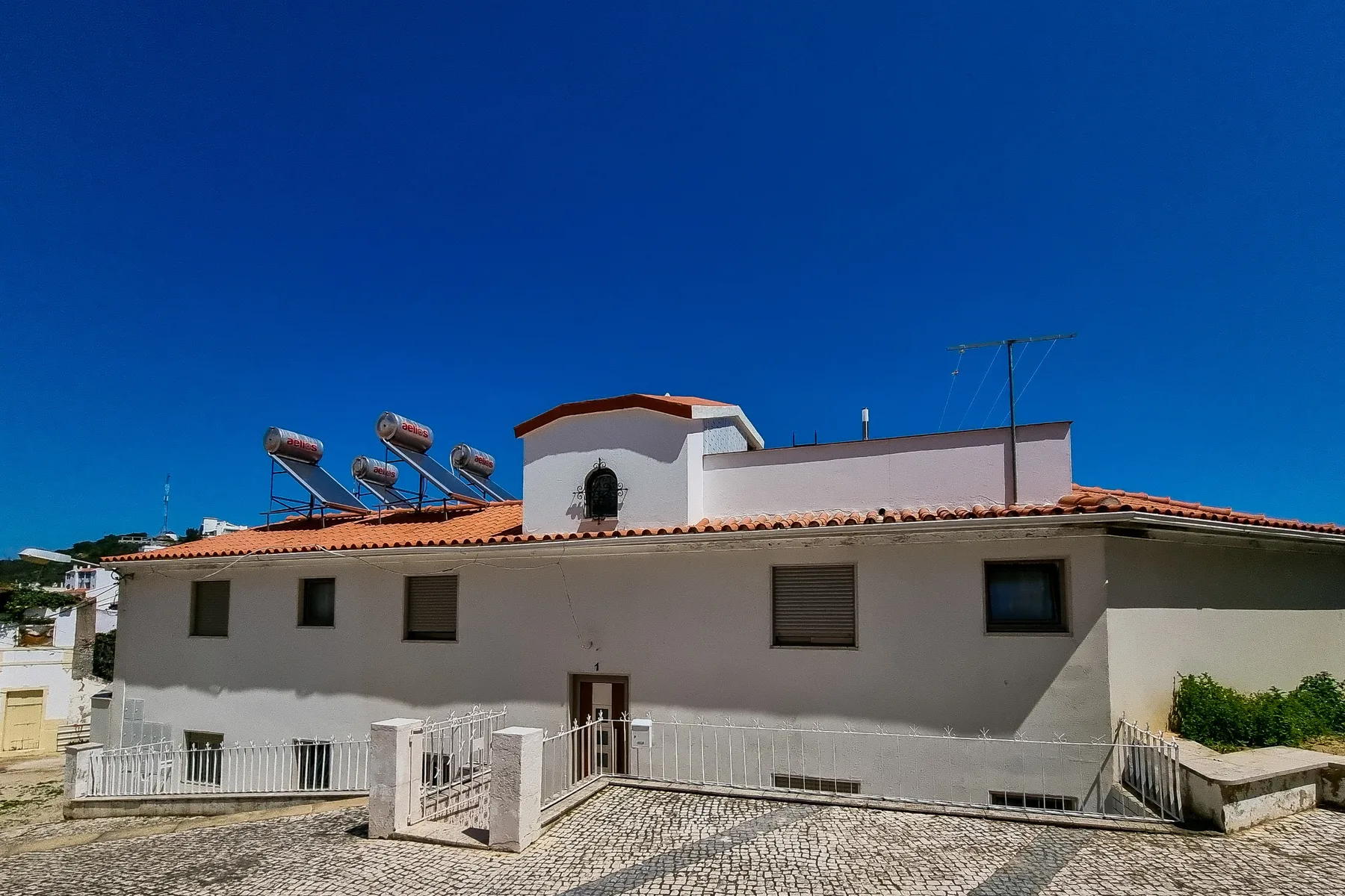 A low-rise residential building with a tiled roof stands beneath a clear blue sky.
