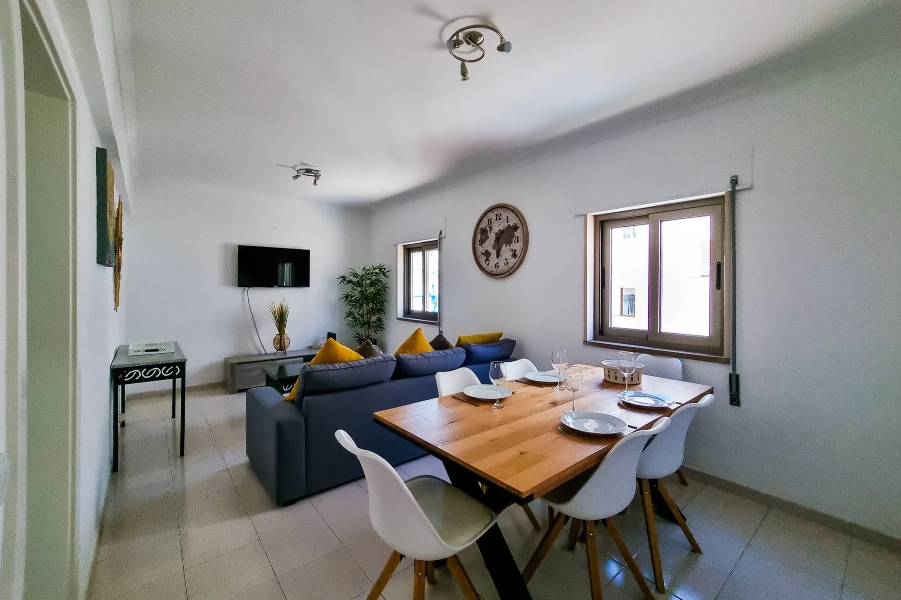 Zona de estar y comedor con un sofá azul y una mesa de madera.