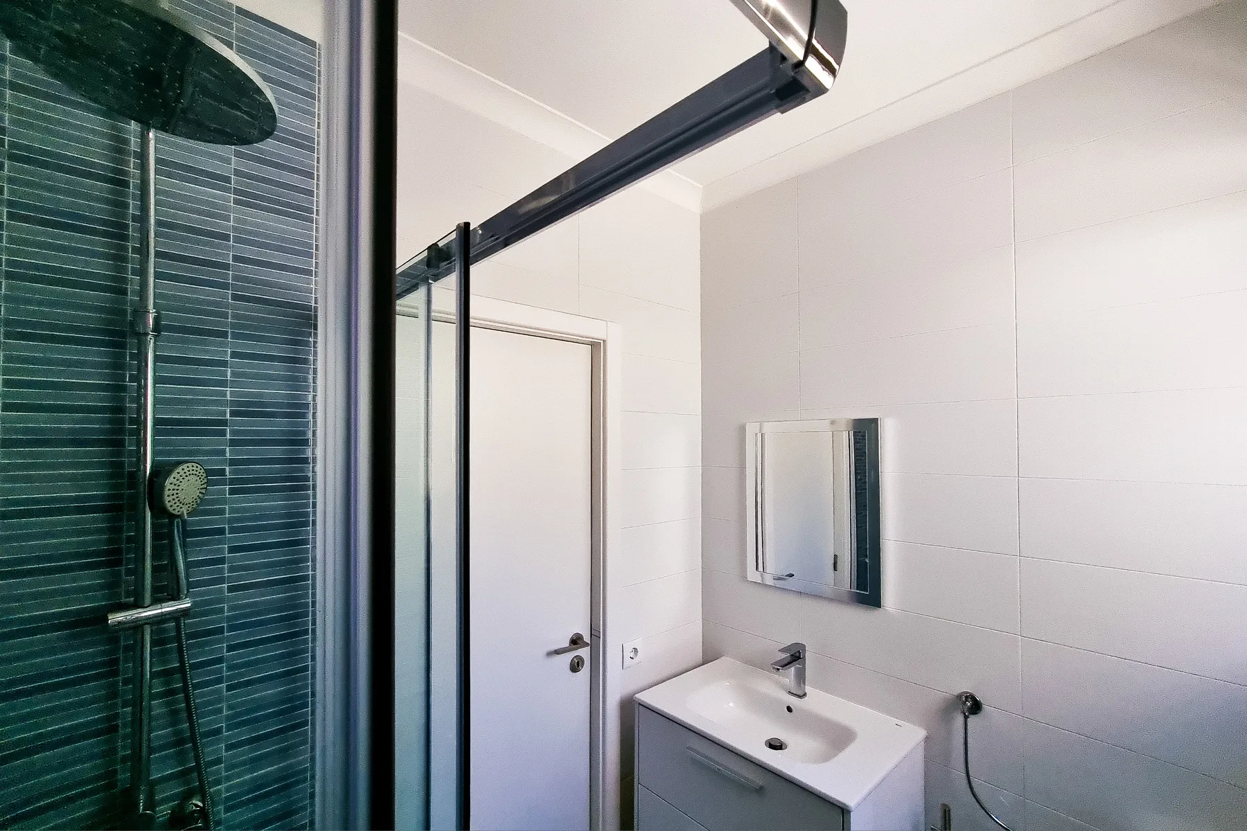 A tiled bathroom with a shower, sink, and mirrored cabinet.